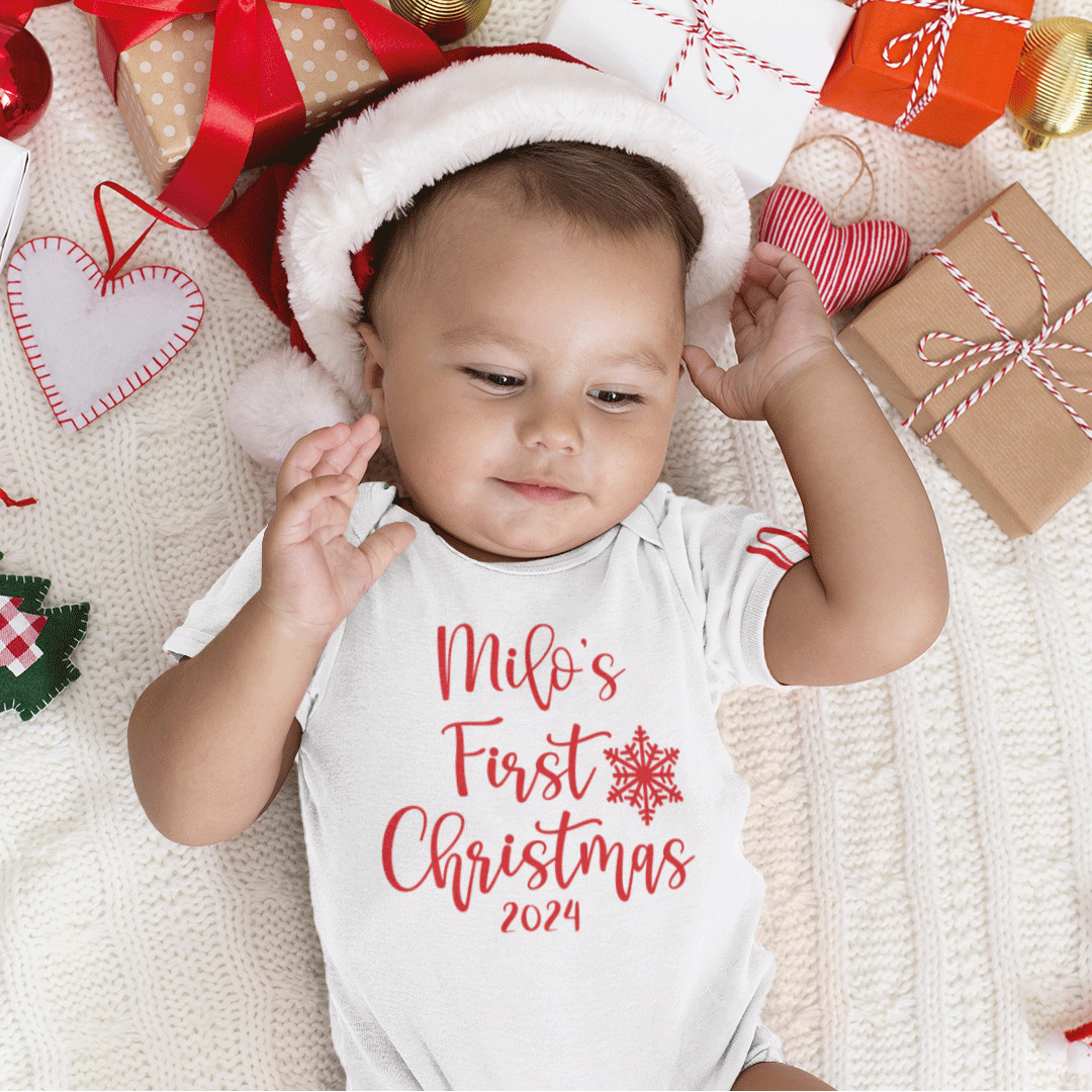 Image of baby in a santa's hat with a white babyvest saying 'Milo's first christmas 2024'