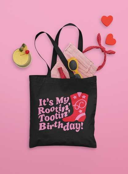 Black tote bag with the words it's my rootin' tootin birthday! in pink text with a pink and red cowboy boot to the right of the text