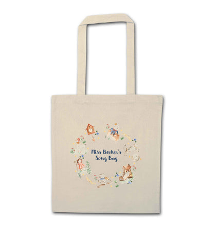 Image shows a cream coloured tote bag. Printed on the bag is some colourful illustrations from nursery rhymes, humpty dumpty, little bo peep, a clock, a boot, a goos, a cat and the fiddle and a cow and a moon. The watercolour illustrations are arranged in a wreath shape with the words 'Grace's son bang' written in blue in the middle.